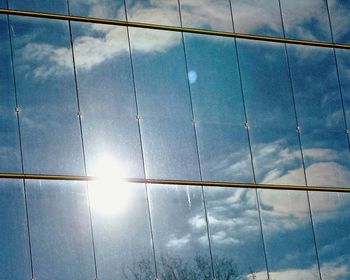 Low angle view of glass building against sky on sunny day