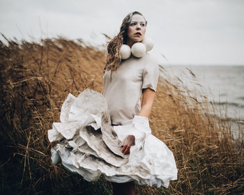 Woman standing on field by sea against sky