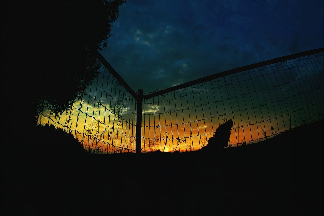 silhouette, sunset, sky, dark, built structure, cloud - sky, low angle view, architecture, dusk, orange color, fence, no people, outdoors, safety, cloud, protection, security, window, nature, wall - building feature