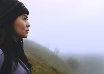 Side view of young woman against sky