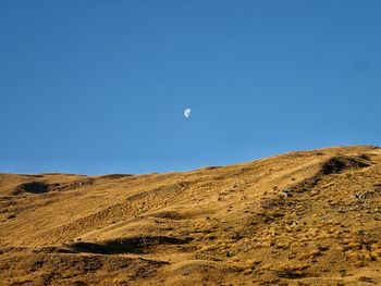 Low angle view of desert against clear blue sky