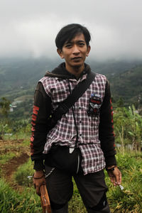 Portrait of young man standing against mountain