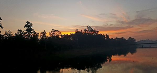 Reflection of trees in lake against sky during sunset