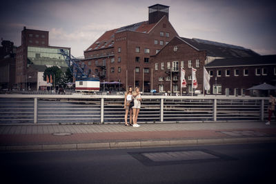 Woman standing on street against buildings in city