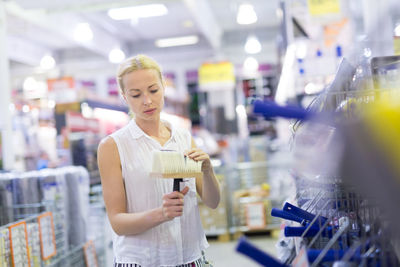 Woman holding camera while standing in store