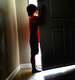 Side view of boy standing at entrance of home