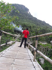 Rear view of man walking on footbridge