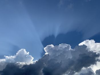 Low angle view of sunlight streaming through clouds