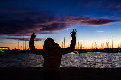 People at harbor against cloudy sky