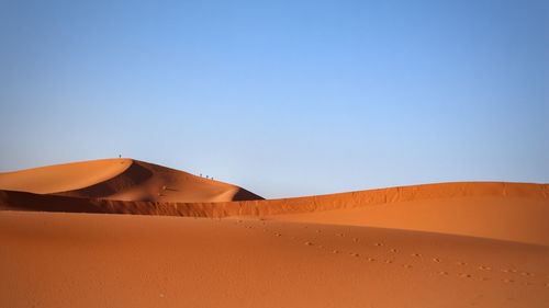 Sand dunes in desert against clear blue sky