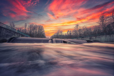 Scenic view of snow covered trees against orange sky