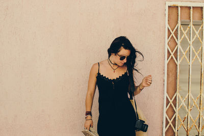 Young woman standing by wall