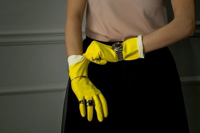 Midsection of woman wearing yellow gloves