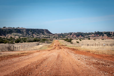 Dirt road amidst landscape against sky