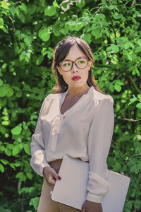 Portrait of young woman standing against plants