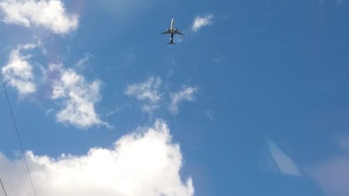 Low angle view of airplane wing against blue sky