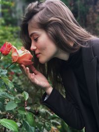 Close-up of beautiful young woman with flowers against blurred background
