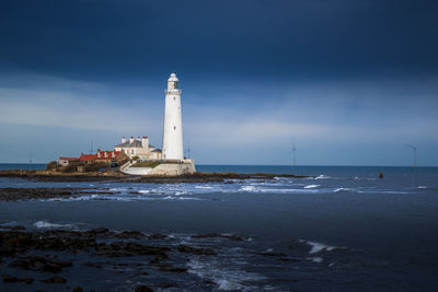 Lighthouse by sea against sky