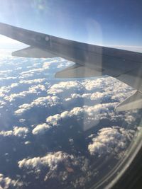 Cropped image of airplane wing over clouds