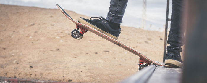 Low section of man standing on skateboard outdoors