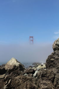 Golden gate bridge during foggy weather against sky on sunny day