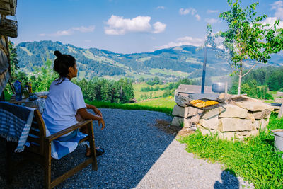 Rear view of woman sitting on seat against mountain