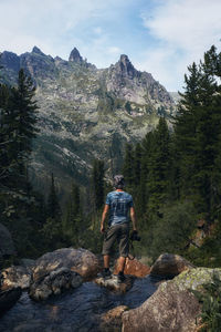 Rear view of man on rocks against mountains