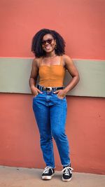 Portrait of young woman standing against yellow wall