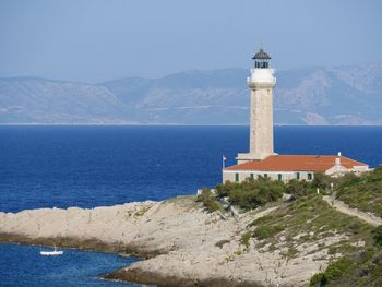 Lighthouse by sea against sky