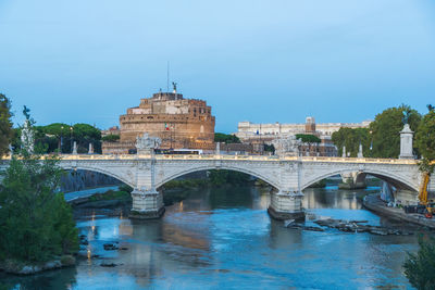 Arch bridge over river against sky in city