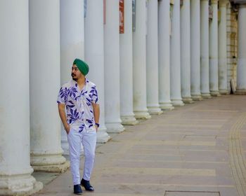 Full length of man standing on footpath against building