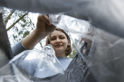 Woman putting plastic bottles in garbage bag