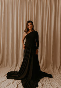 Portrait of young woman standing against curtain