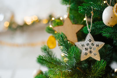 The christmas tree is decorated with toys, golden stars, white eggs and garlands in close-up.