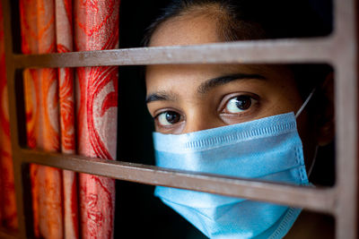 Close-up of woman wearing mask seen through window