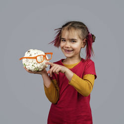 Portrait of smiling girl holding ice cream against gray background