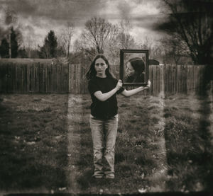 Portrait of smiling boy standing on field against trees