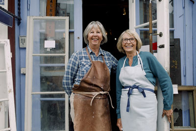 Portrait of cheerful senior female coworkers standing at store entrance