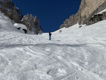 Person walking on snowcapped mountain against sky