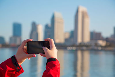 Female hands hold a mobile phone. girl is taking pictures of san diego downtown on her mobile phone