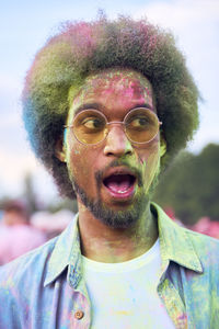 Close-up of surprised man covered with powder paint at carnival