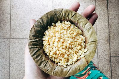 Cropped hand of person holding mung bean snack in container