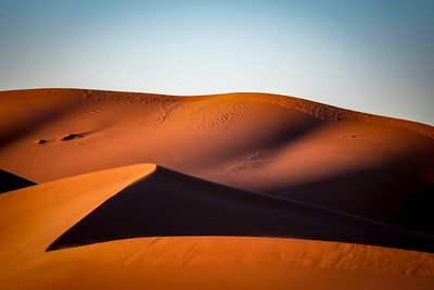 Sand dunes in desert against clear sky