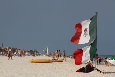 People on beach against clear sky