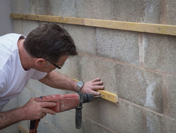 Carpenter drilling on wall