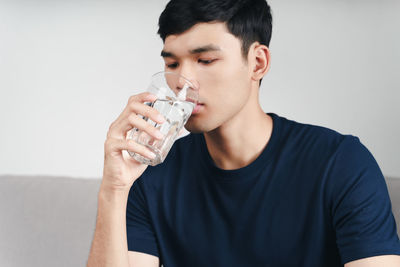 Portrait of young man drinking glasses against white background