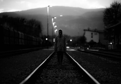 Woman wearing mask standing on railroad track