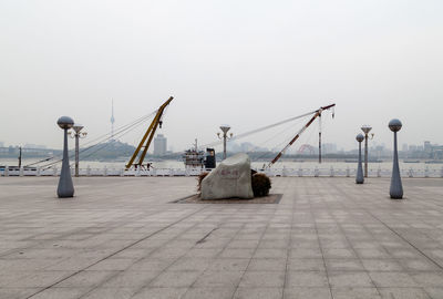 Cranes by pier against clear sky