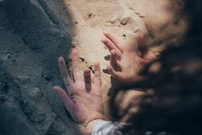 High angle view of hands on sand