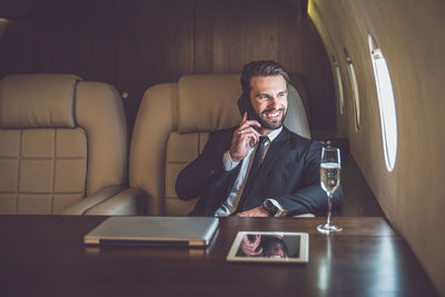 Businessman talking over mobile phone while sitting in air vehicle